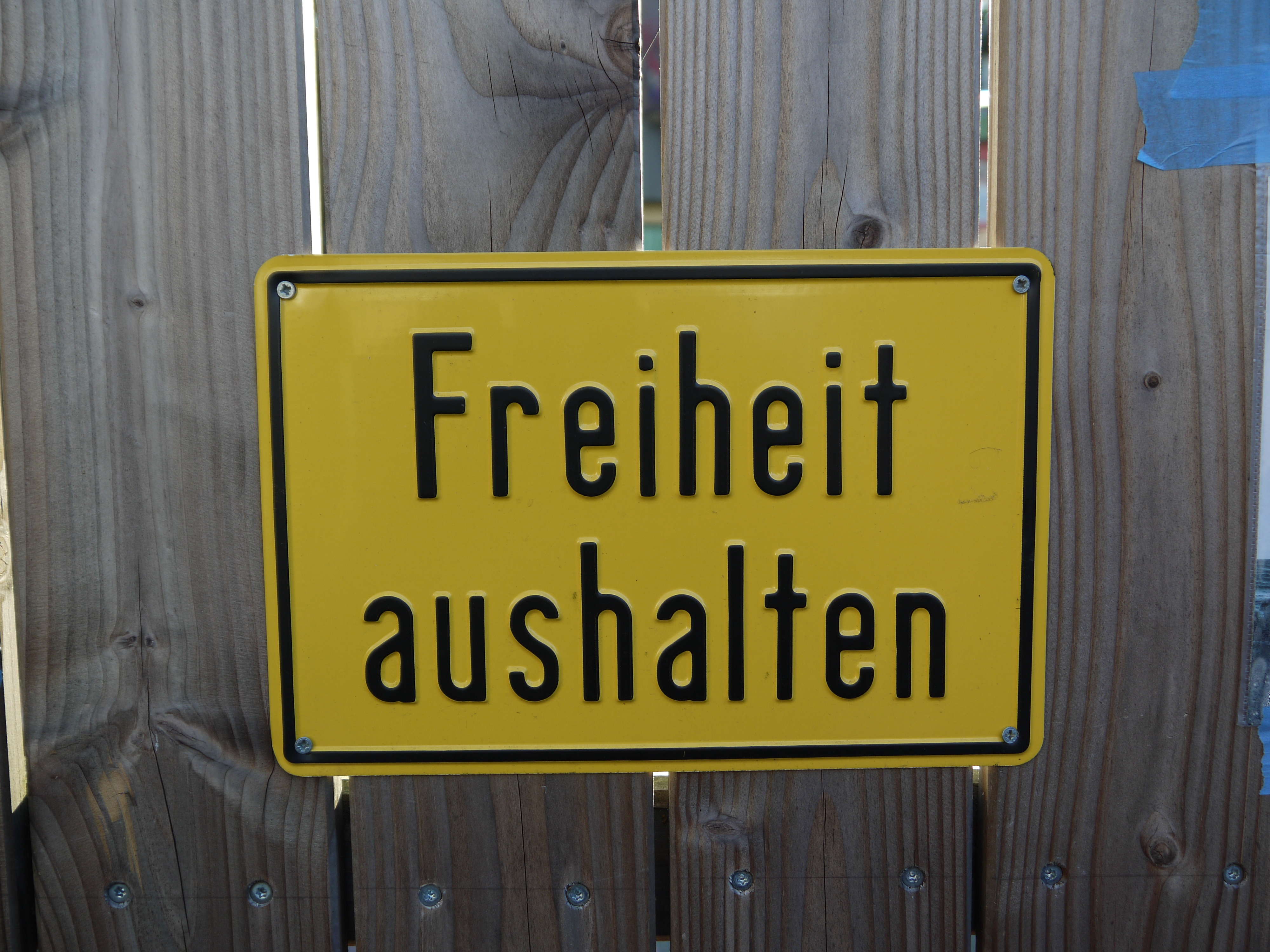 Gartenzaun mit einem gelben Schild mit der Aufschrift: 